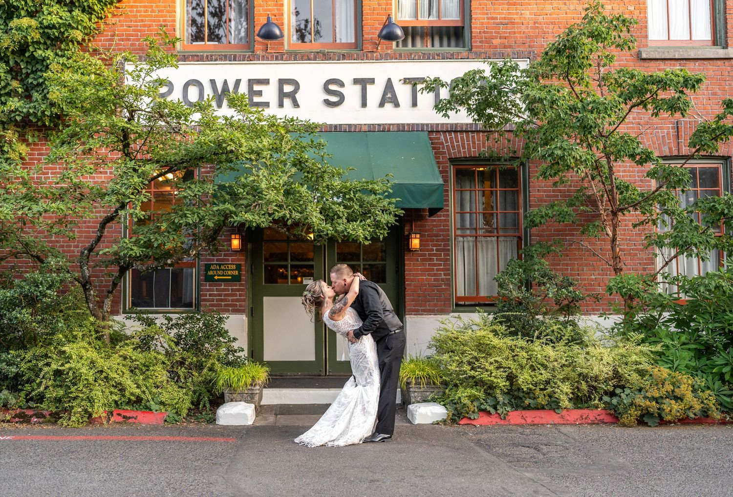 A romantic wedding moment captured outside the historic Power Station building surrounded by greenery.