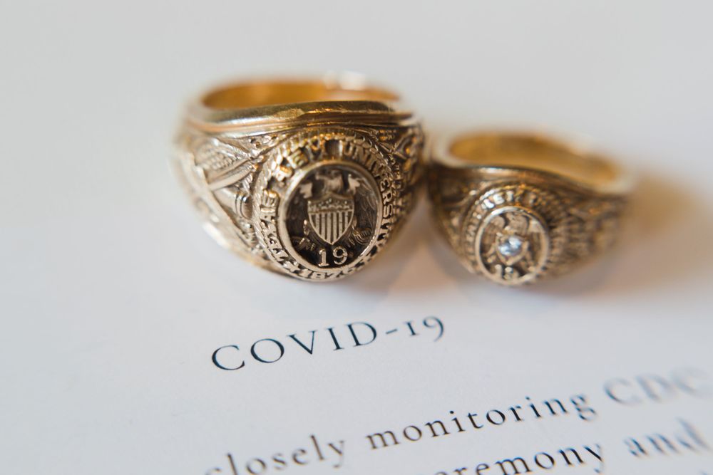 Two ornate gold rings photographed on a document with COVID-19 text visible.