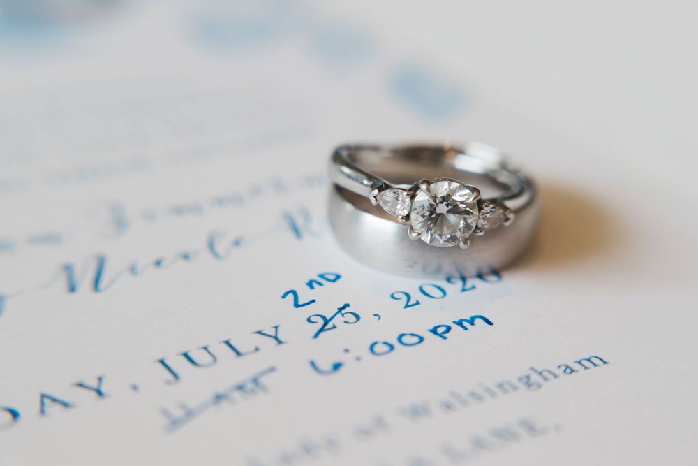 Diamond engagement ring photographed on blue wedding invitation text.