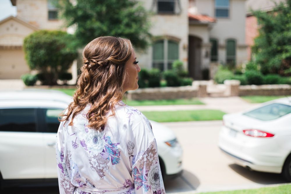 Person in floral robe with styled hair looking away in a suburban setting.