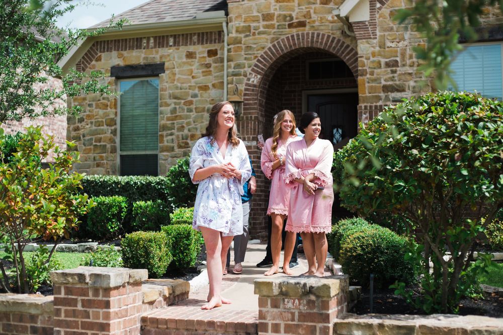 Wedding party members in robes standing on stone steps outside a home with architectural details.