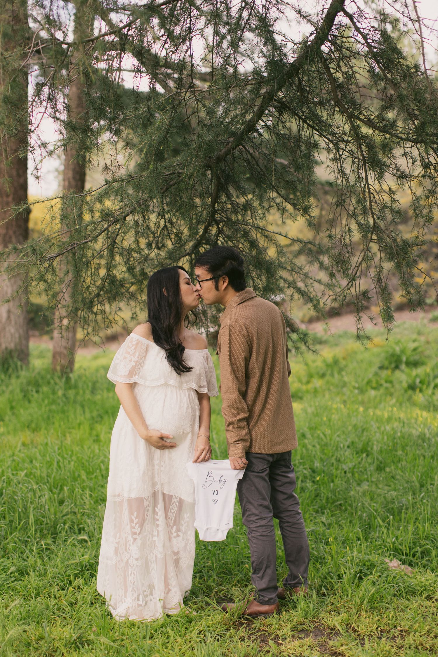 Couple in casual attire sharing an intimate moment during outdoor maternity photoshoot.
