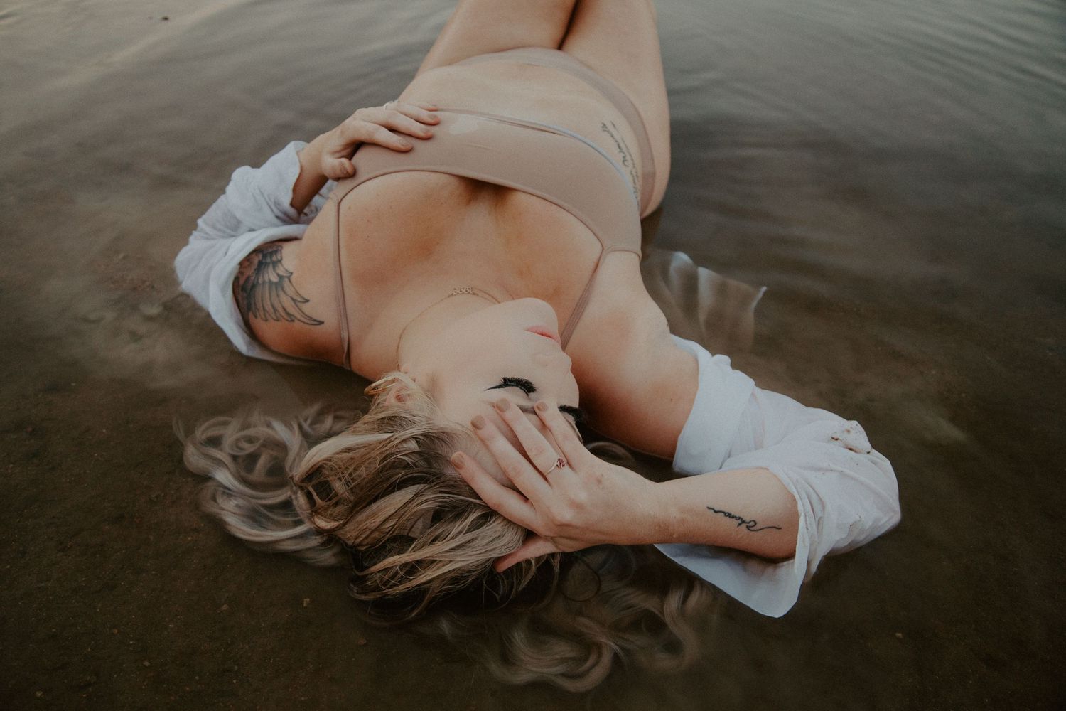 empowered woman in the water during boudoir session, who is clothed in white button up and tan two piece calvin klein