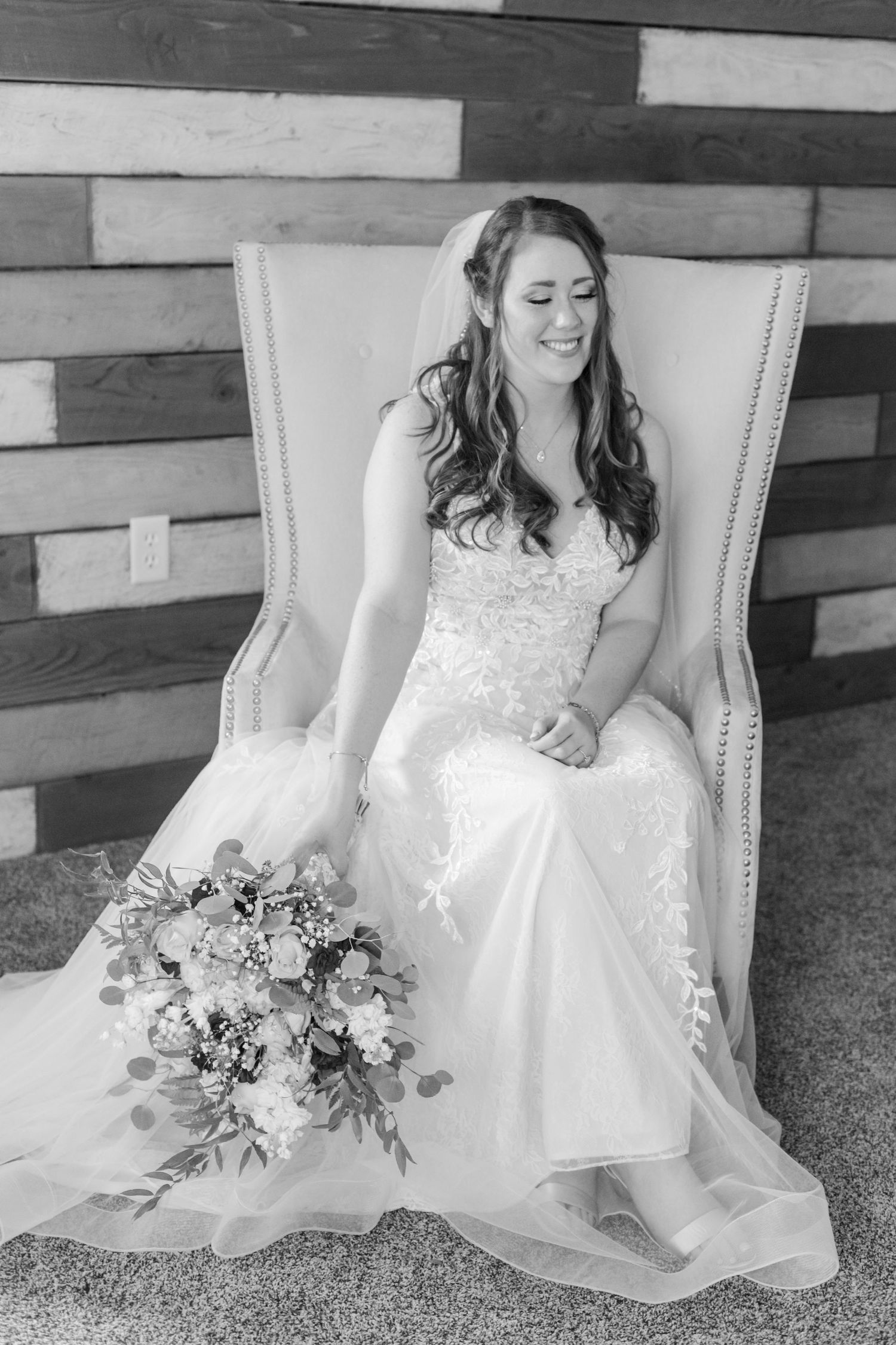 A wedding bouquet with mixed flowers sits in the lap of a white lace dress.