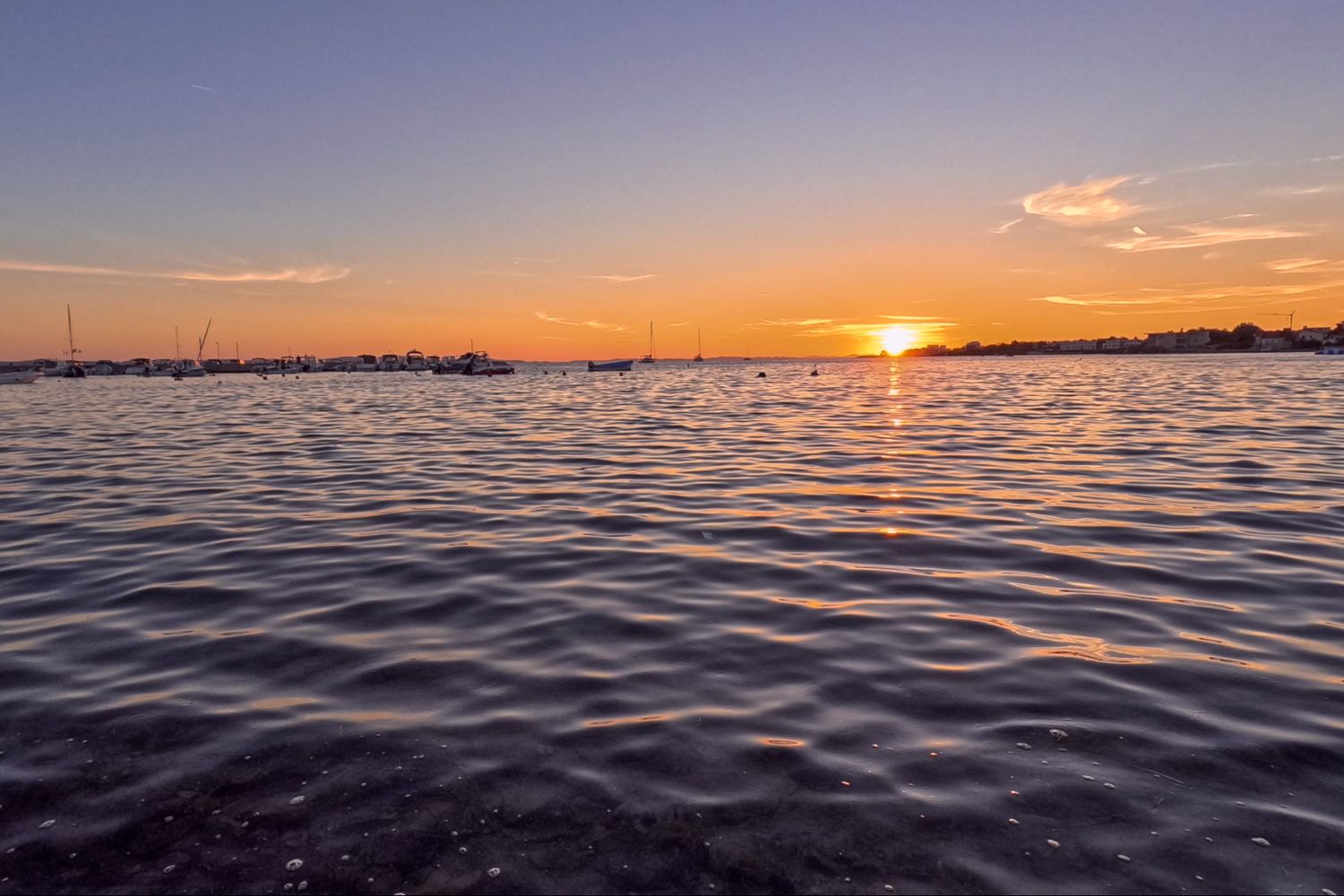Sunset over rippling water creates golden reflections on lake surface.