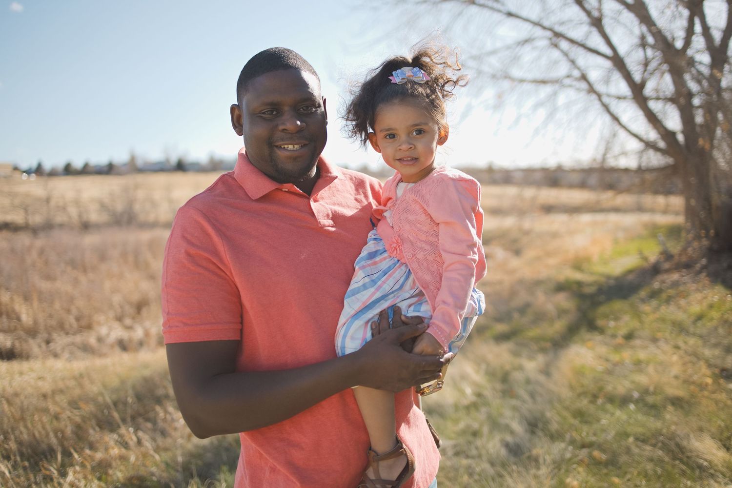 dad holding toddler daughter wearing pink outdoor spring photoshoot