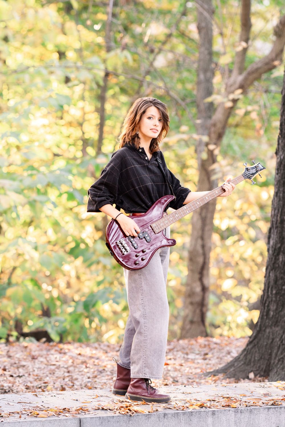 Senior with her guitar on Roosevelt Island with fall foliage and showing her personality
