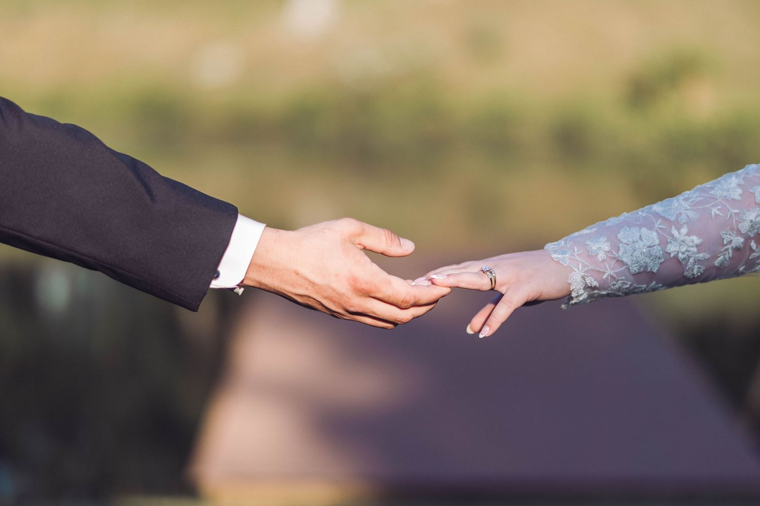 Close-up shot of two hands reaching toward each other against a blurred outdoor background.