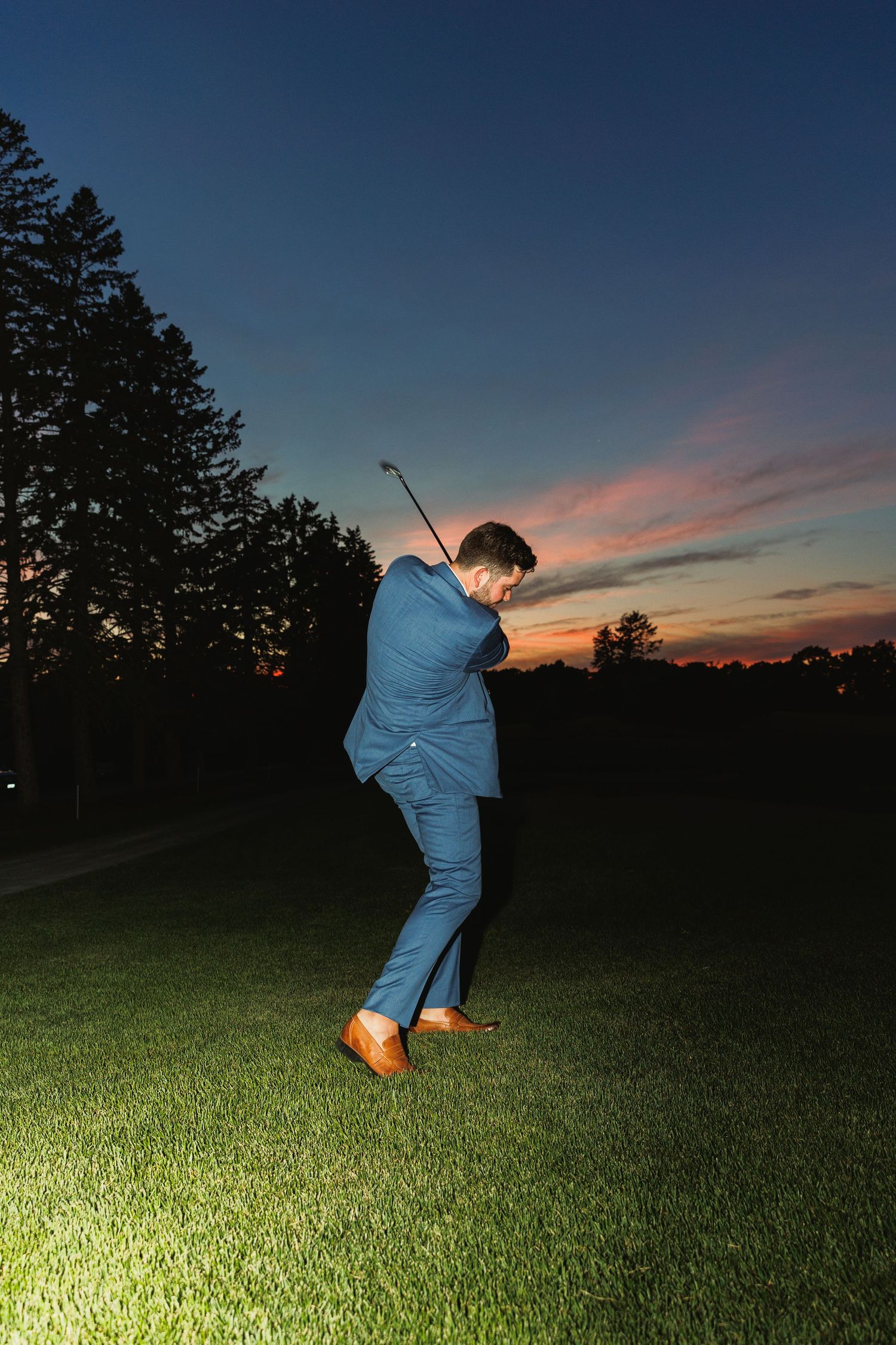 Silhouette of someone dancing on a golf course against a colorful sunset sky.
