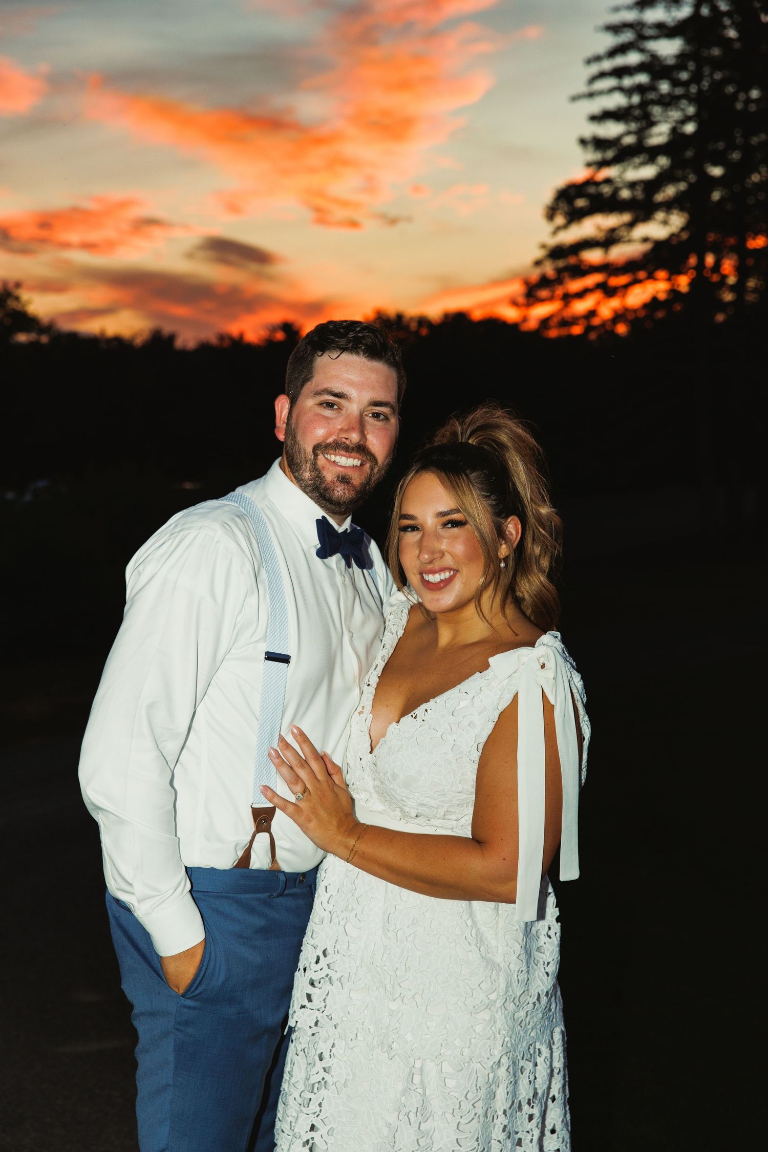 Sunset wedding portrait with dramatic orange and pink sky.