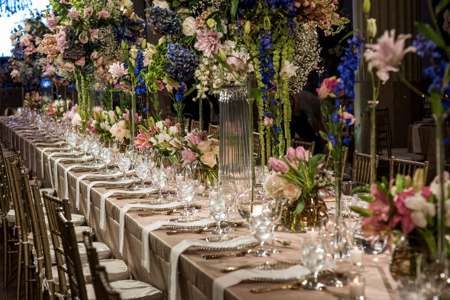Luxurious wedding reception table settings with tall floral centerpieces and crystal glassware.