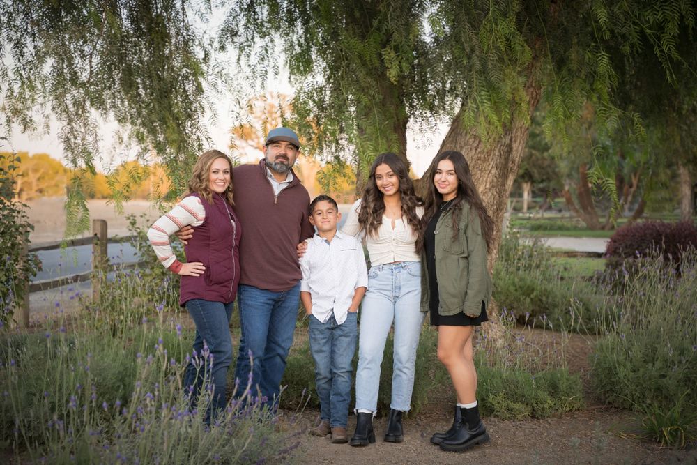 Group photo session with natural backdrop of weeping willow trees at sunset.