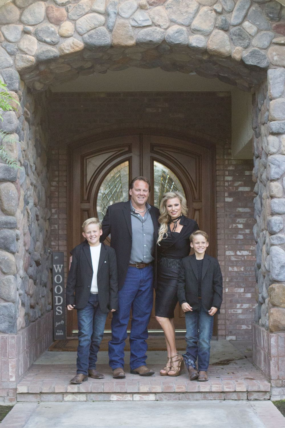 Family group photo taken under stone archway entrance of rustic building.