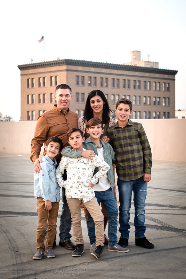 Family portrait against urban backdrop with tall building and sunset sky.