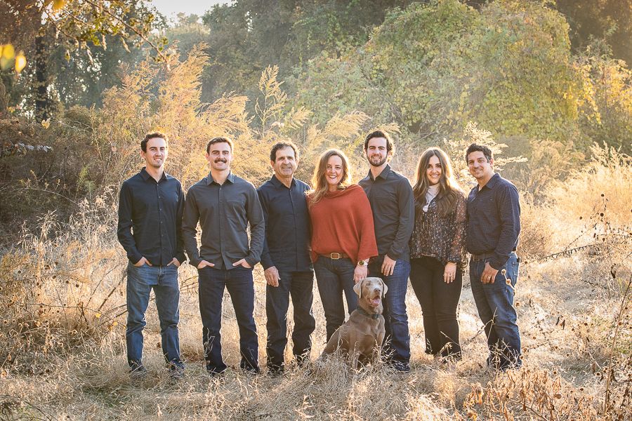 Large group standing in row against golden autumn foliage background.