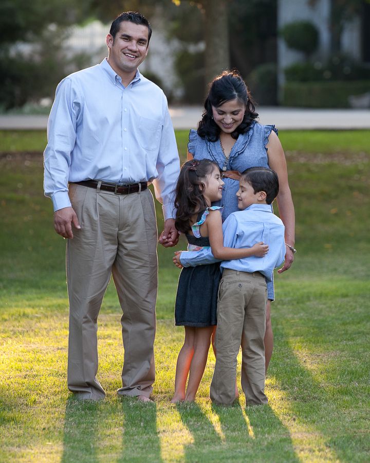 Family interacting on sunlit lawn wearing coordinated blue and khaki outfits.