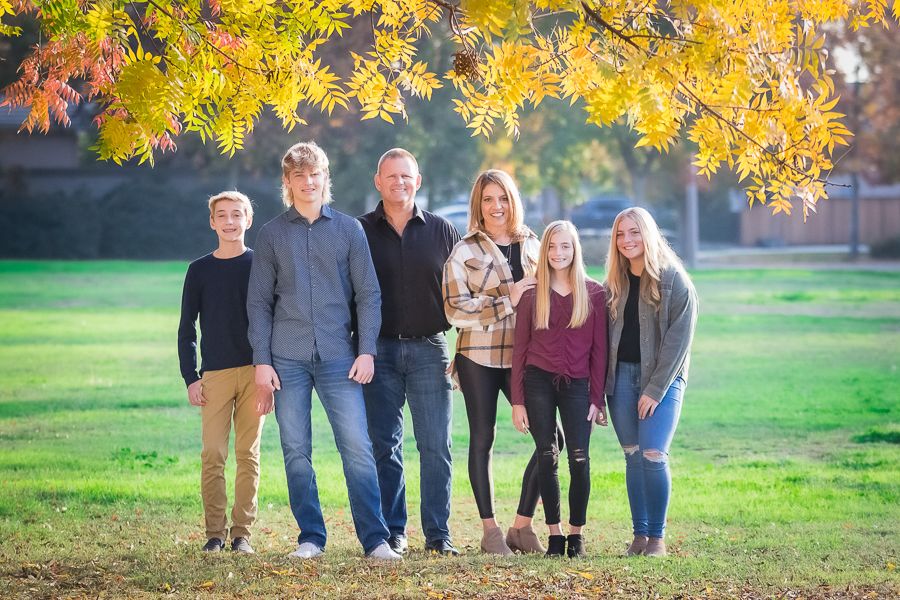 Group portrait session against autumn foliage background with golden sunlight.