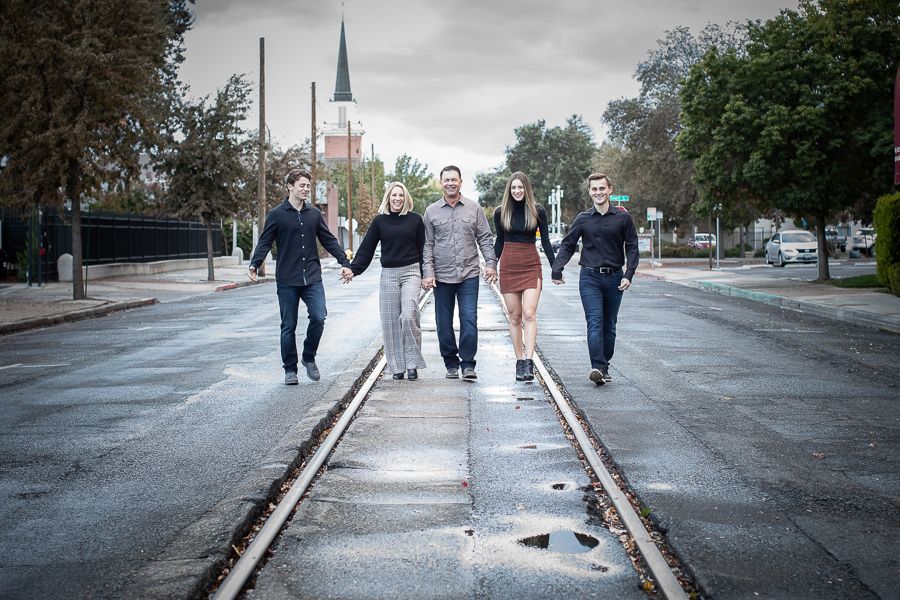 Urban photo shoot with family members walking along a gray sidewalk.