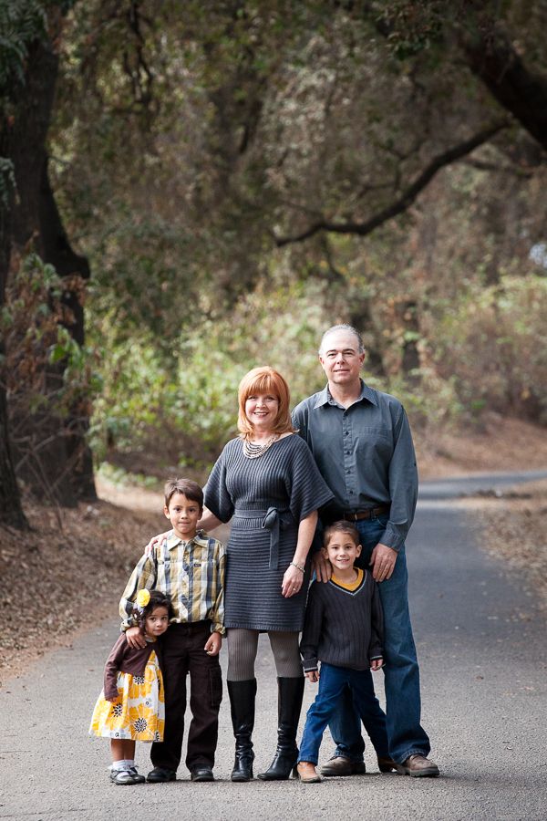 Family portrait series on paved path surrounded by trees.