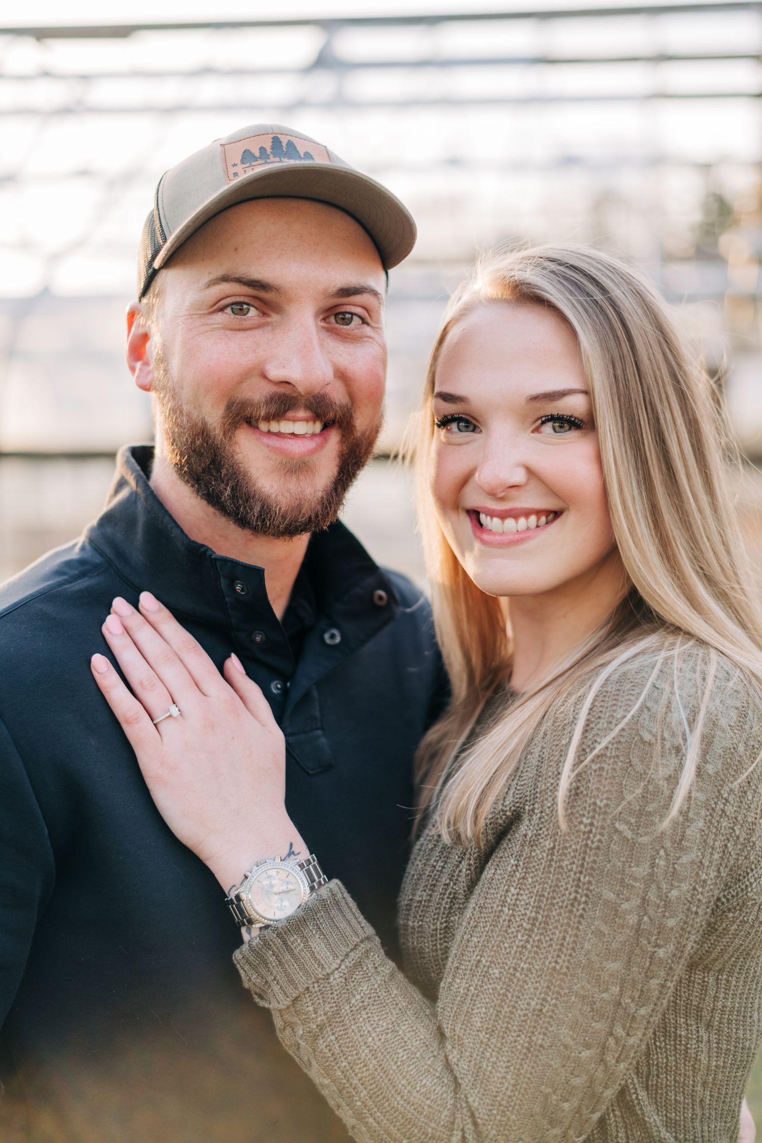 engaged couple smiling and looking at the camera