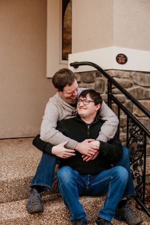 Couple sharing intimate moments while sitting on outdoor steps at dusk.