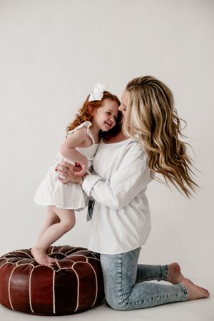 Sweet candid moments of parent and child laughing together while sitting on brown leather ottoman.