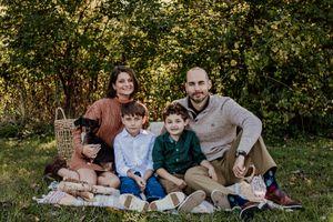 Family relaxing together on blanket during outdoor photo session in green field.