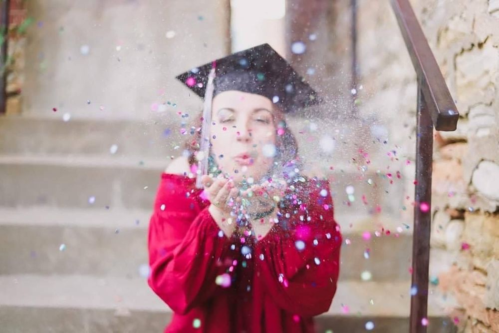 Person in red blowing glitter and confetti in a celebratory moment.