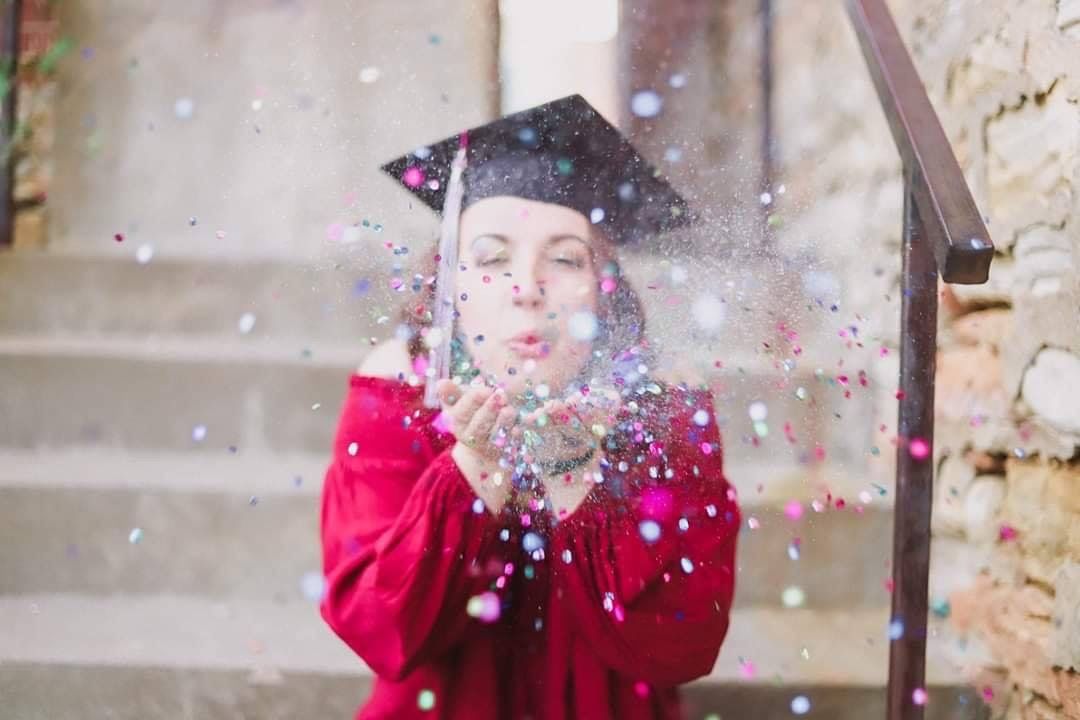 Person in red blowing glitter and confetti in a celebratory moment.
