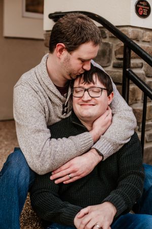 Romantic couple embracing on stone steps in casual winter wear.