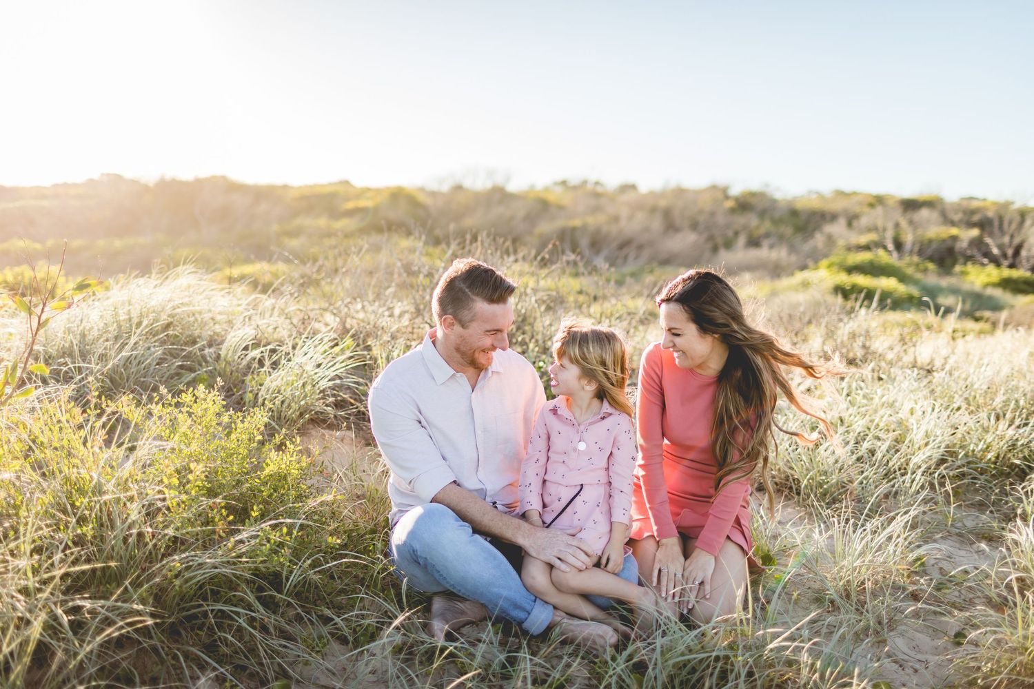 A family enjoys quality time together on a hillside during sunset.