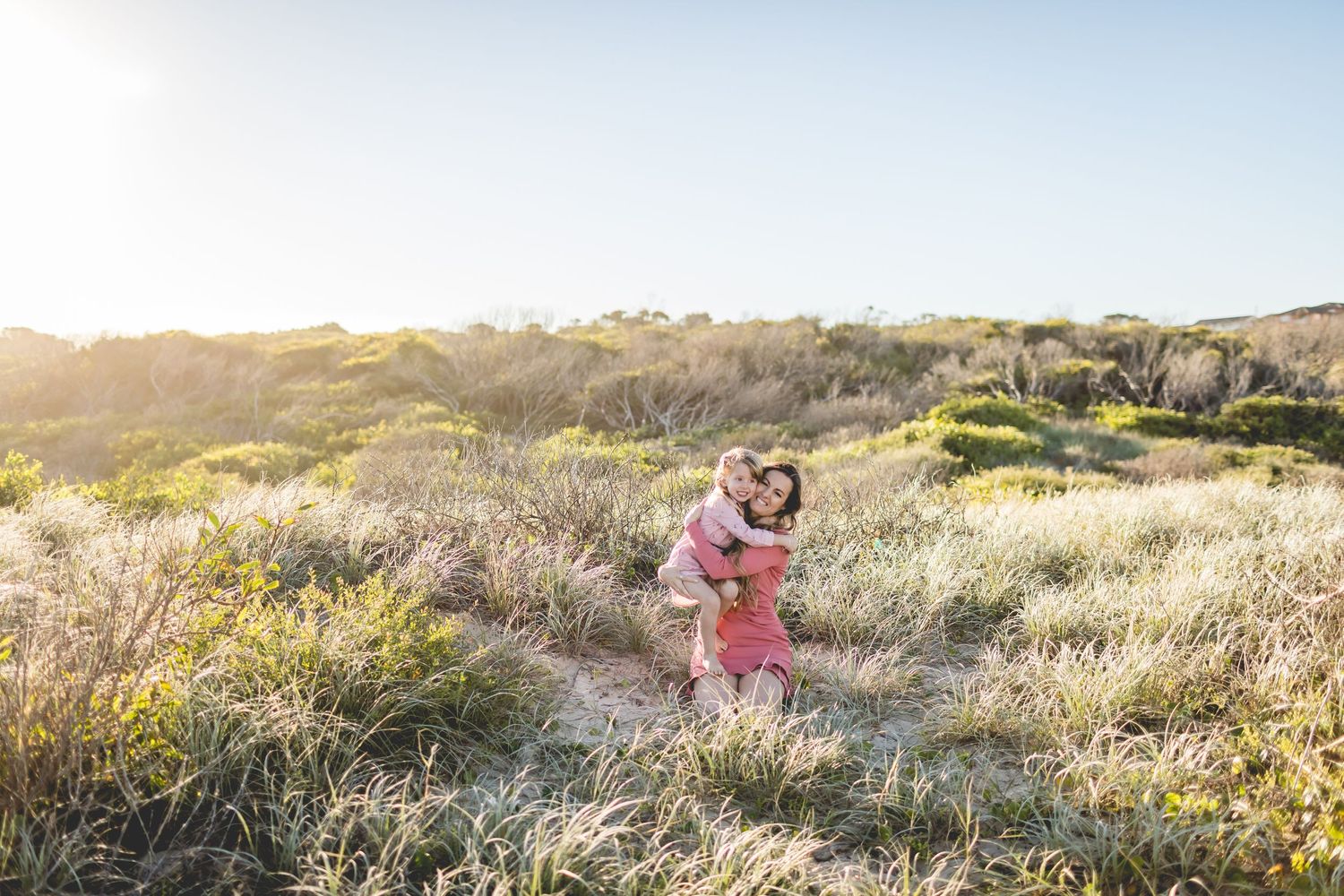 Family enjoying playtime together in scenic field during golden hour.