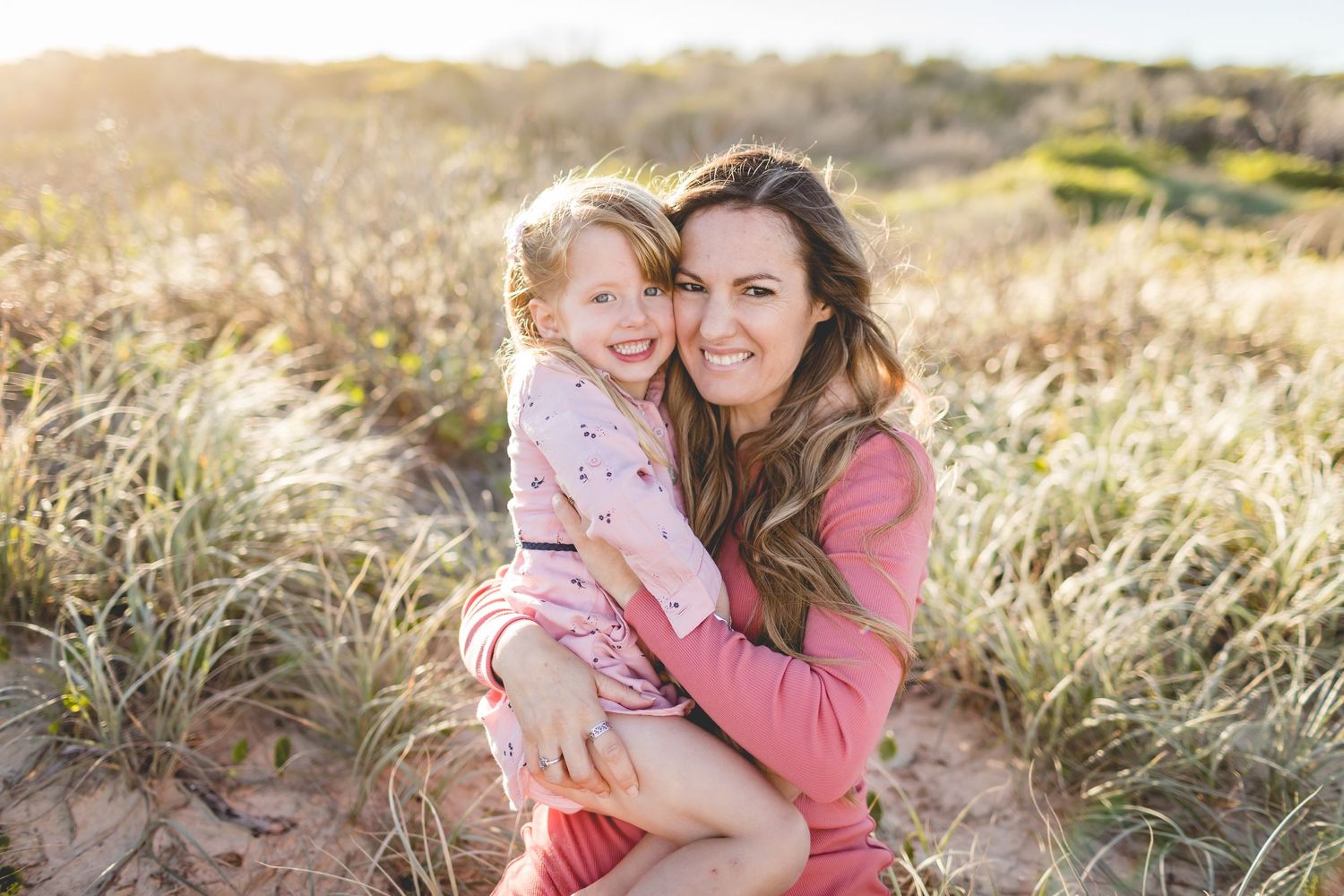 Sweet candid moment captured between parent and child in sunlit meadow.