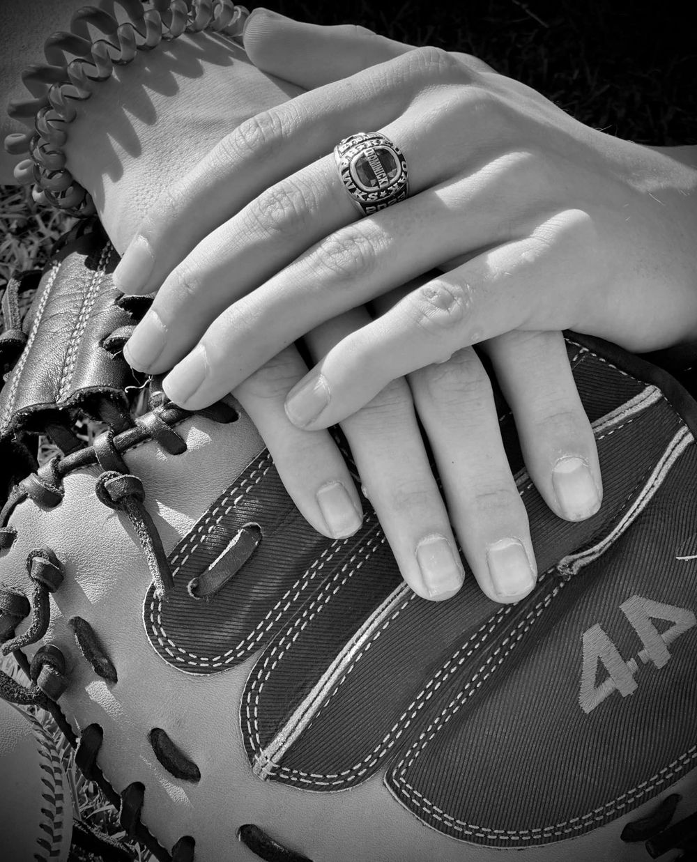 Black and white close-up of an engagement ring on a baseball glove.