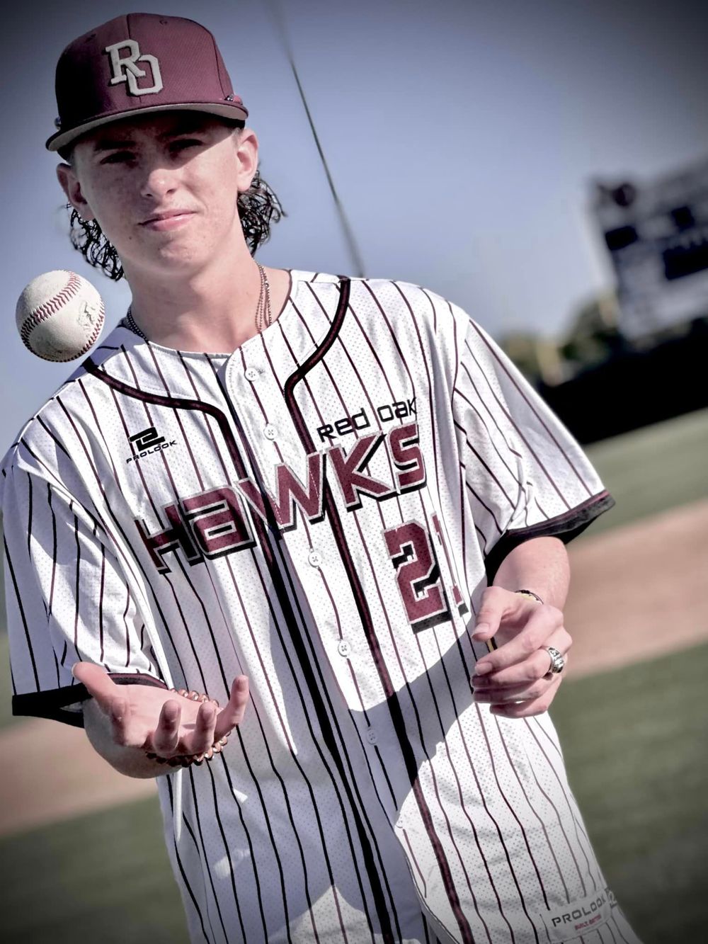 Baseball player in pinstriped uniform tossing a baseball on the field.