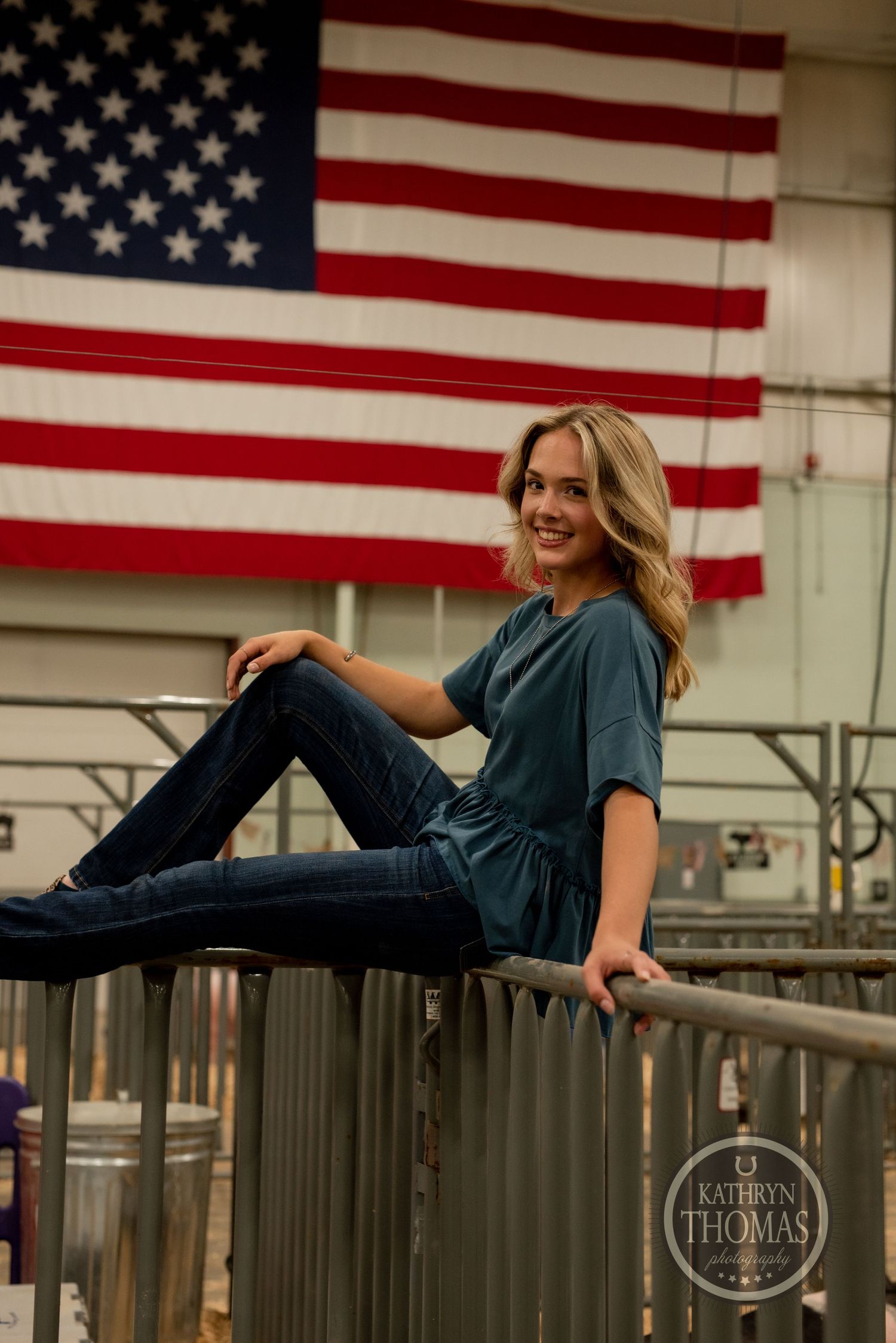 American flag backdrop with someone sitting on metal railing wearing jeans.