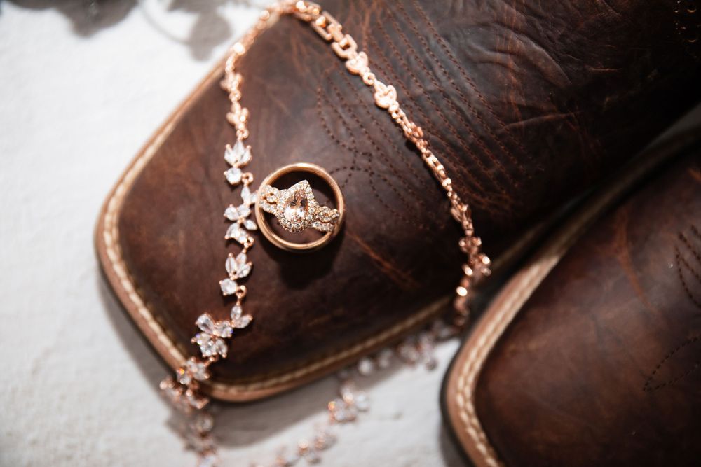 Wedding rings and delicate jewelry arranged on brown leather shoes.