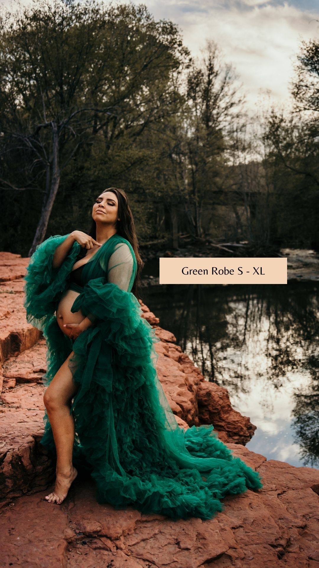 Flowing emerald green tulle gown photographed on red rocks near reflective water.