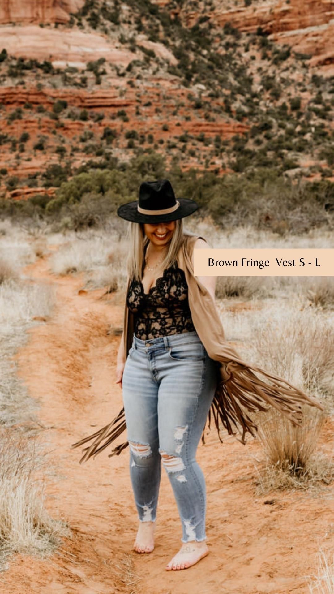 Western style outfit with fringe vest and hat photographed on desert trail with red cliffs.