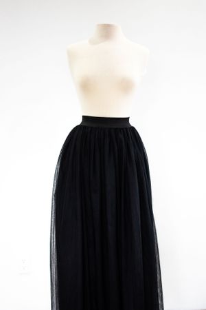 A black tulle maxi skirt shown on a beige dress form mannequin.