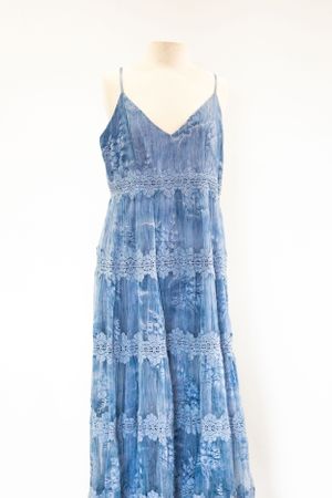 Blue tie-dye maxi dress with lace trim and spaghetti straps on white display mannequin.