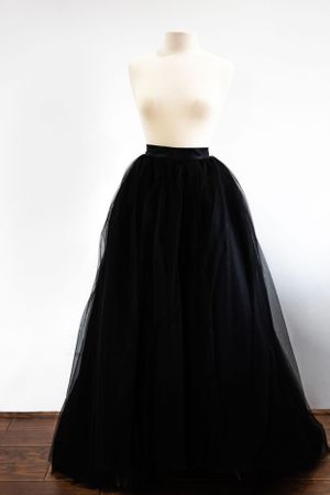 A dramatic black tulle ballgown skirt displayed on a dress form against a white background.