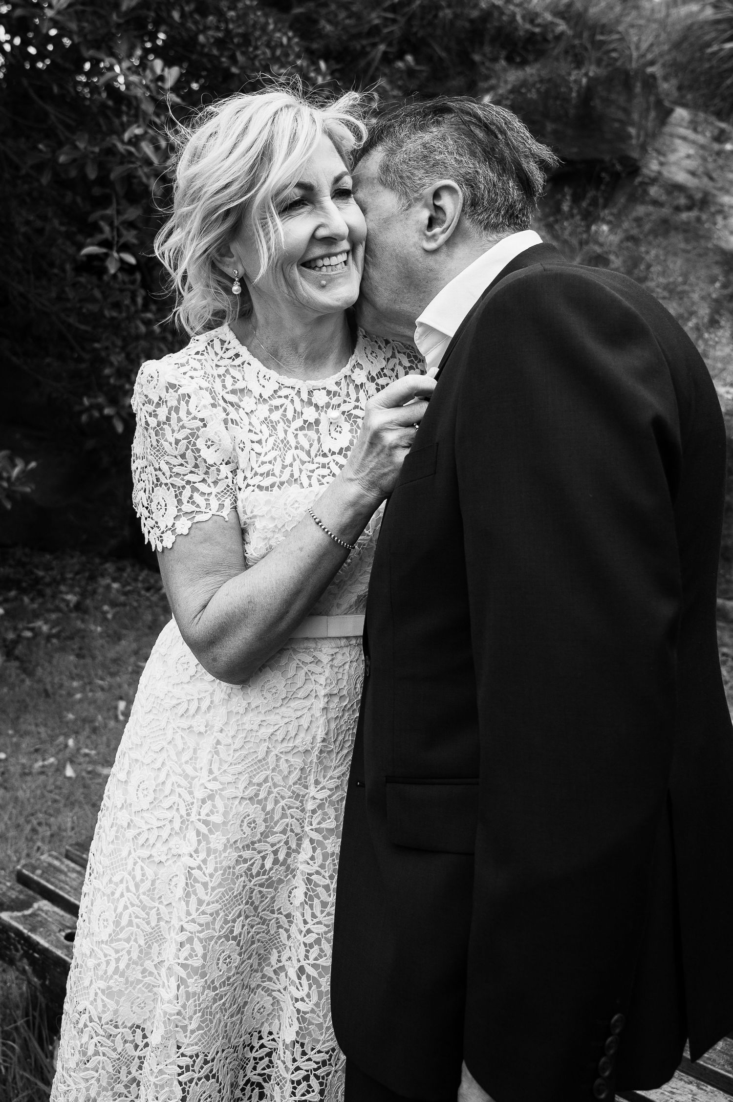 Candid black and white wedding photo showing joyful laughter and embrace.