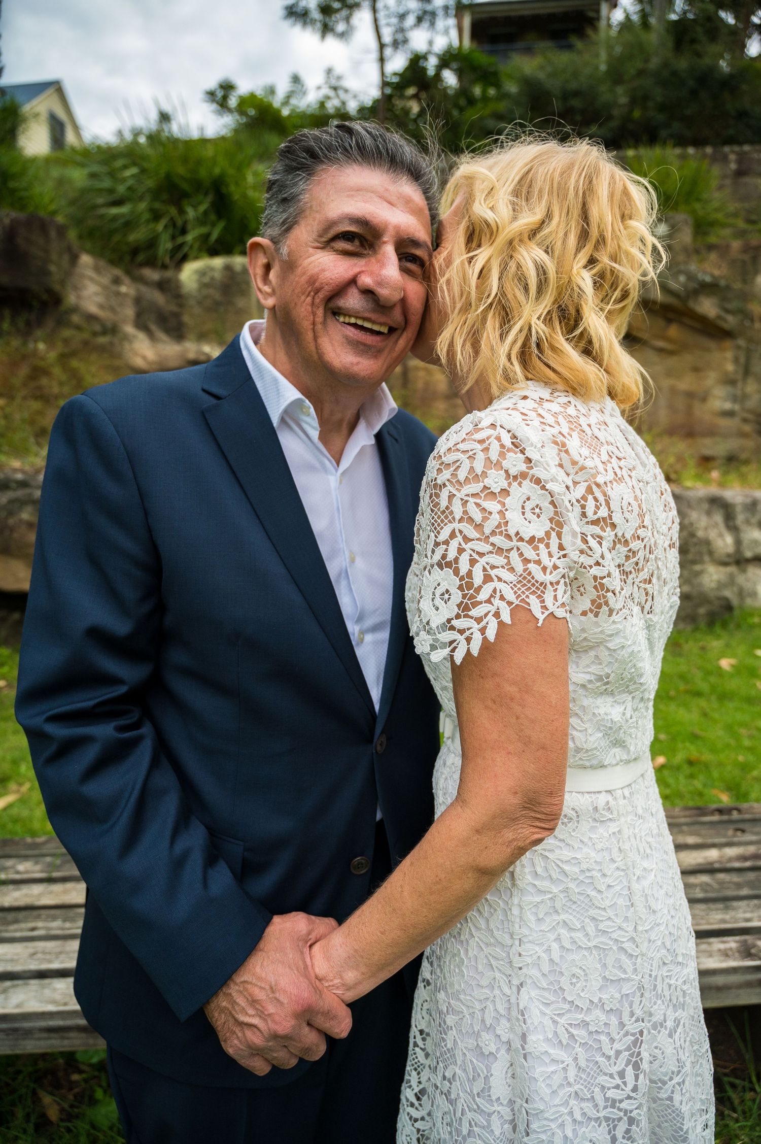 Happy couple in formal attire sharing intimate moment in garden setting.