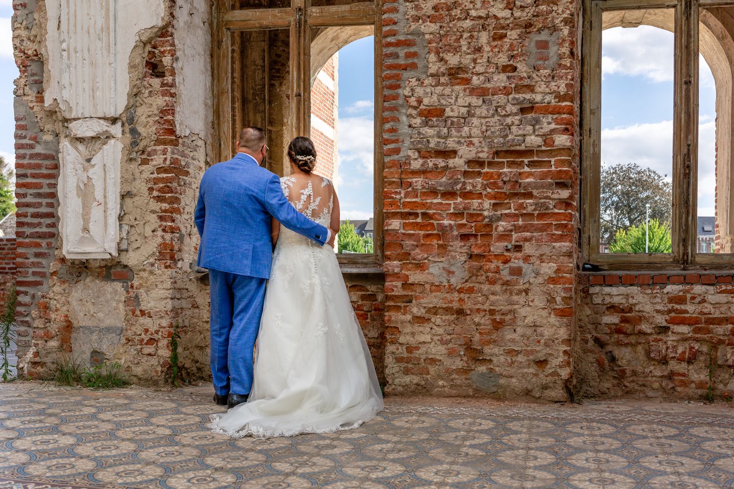 Wedding couple embracing in romantic moment among historic brick ruins.
