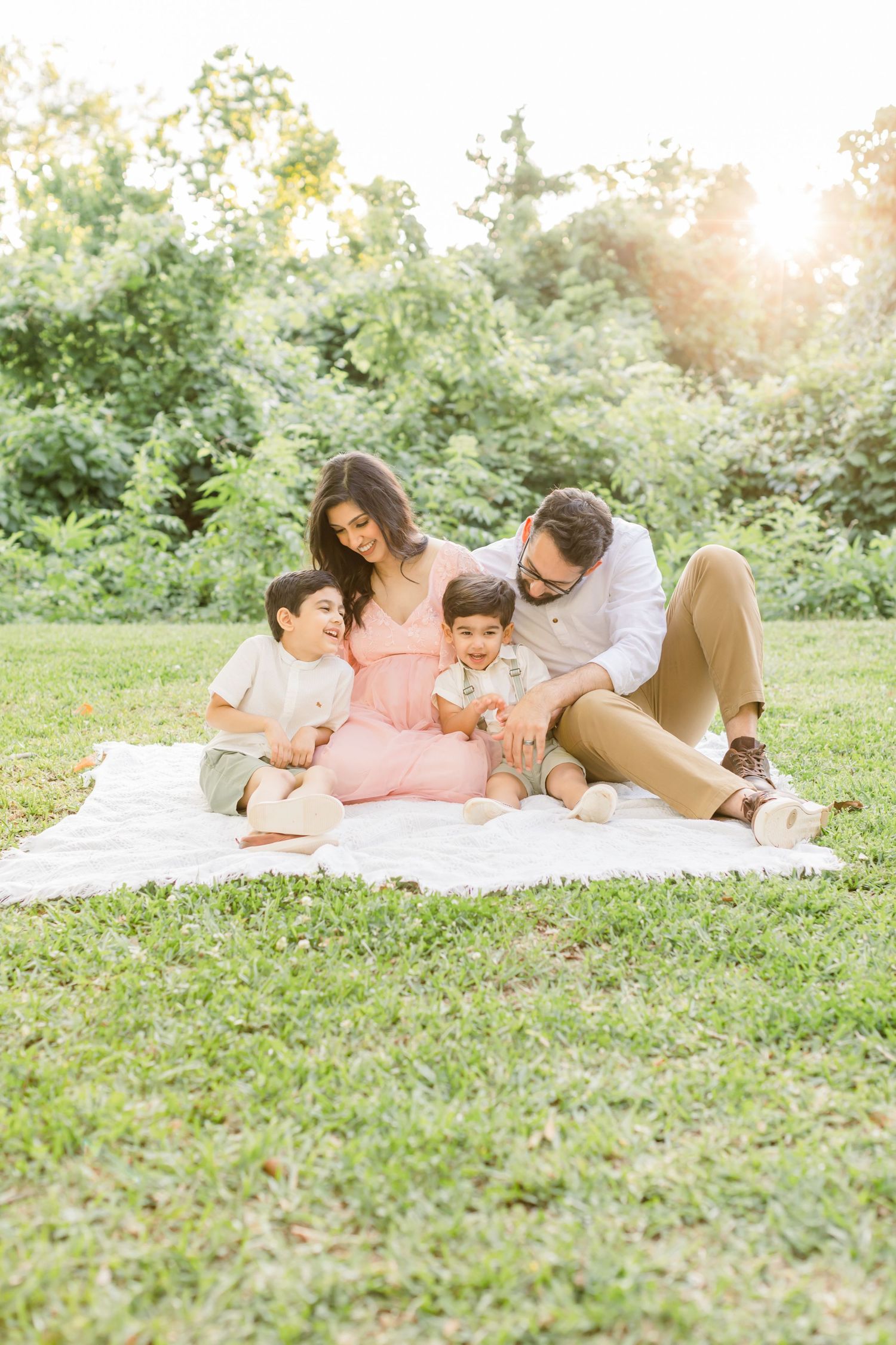 A loving family gathering on a picnic blanket during golden hour in a garden setting.