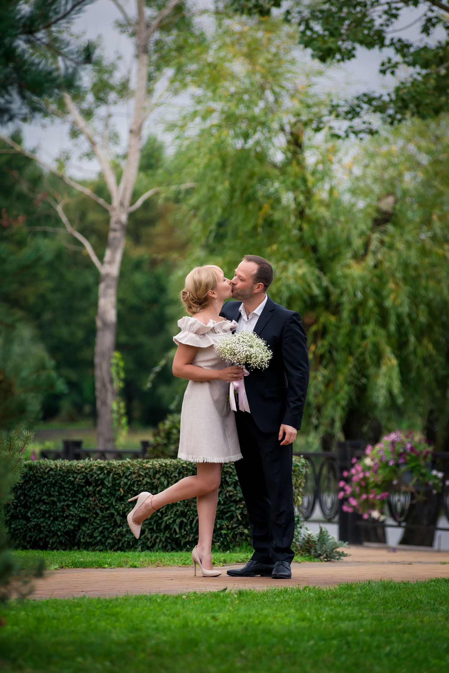 Playful outdoor engagement photos taken in a lush green park setting.