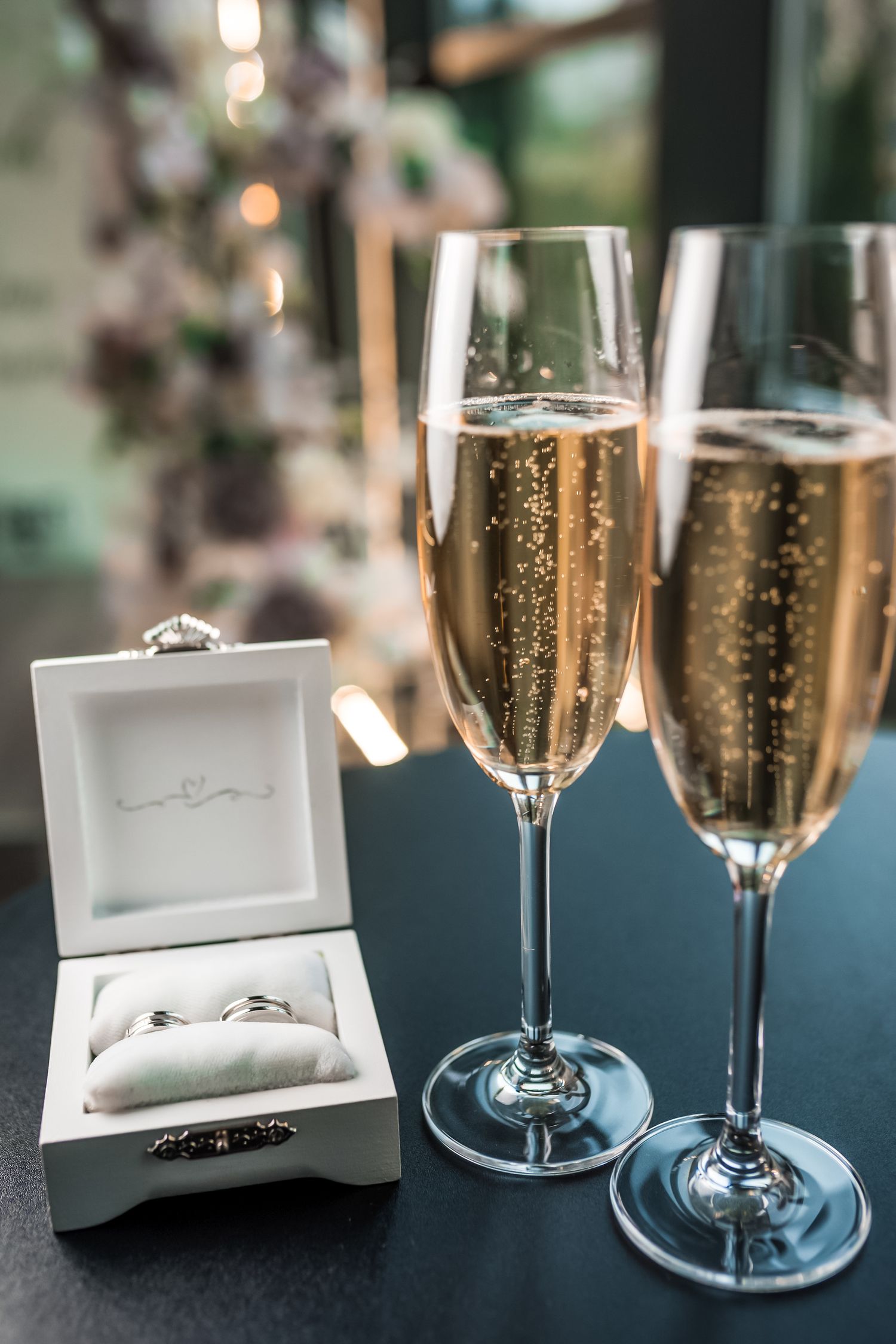 Champagne flutes and wedding rings displayed elegantly with bokeh lighting effects.
