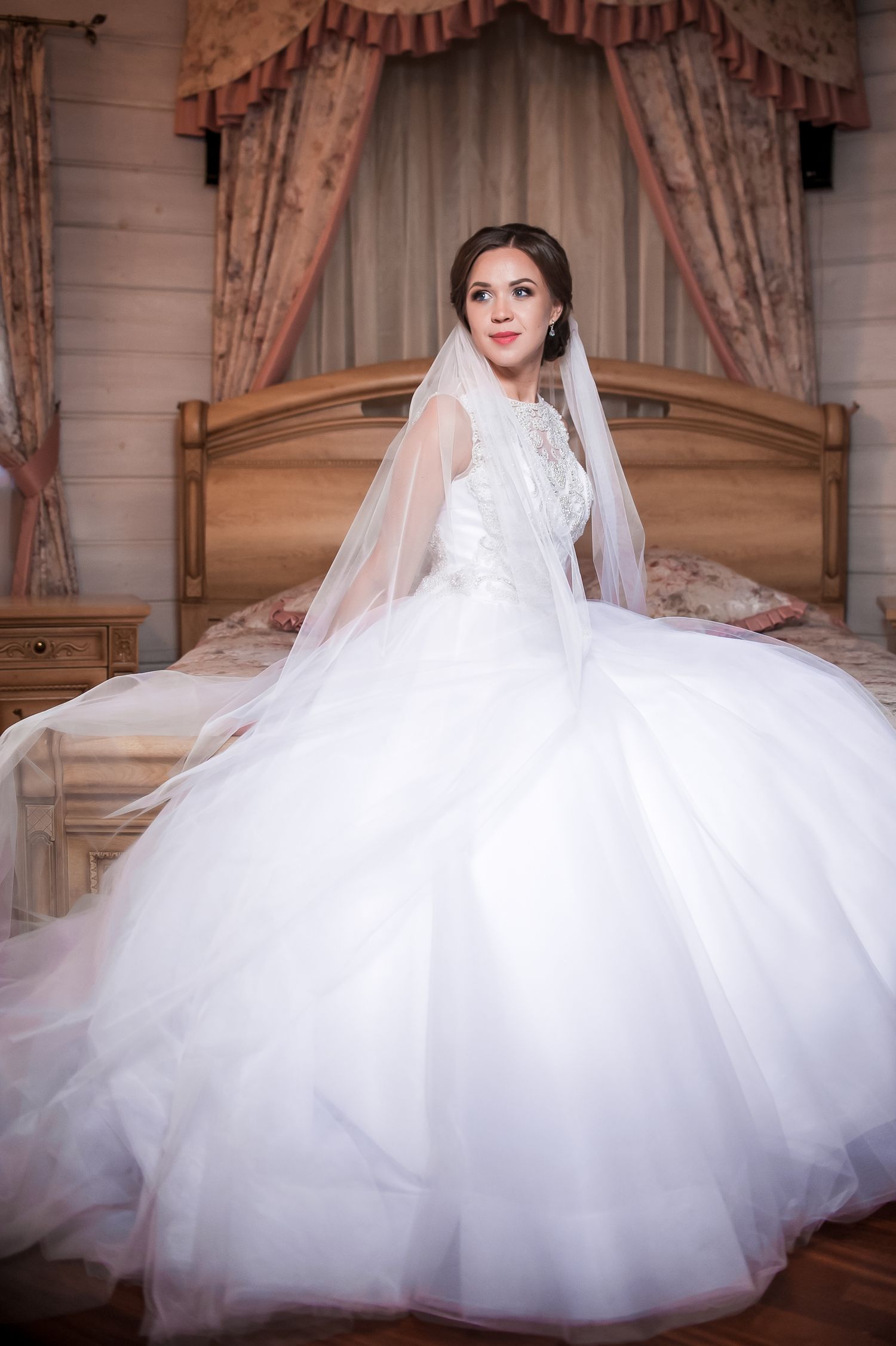 A stunning white wedding gown with a voluminous tulle skirt and lace bodice displayed in an elegant room.