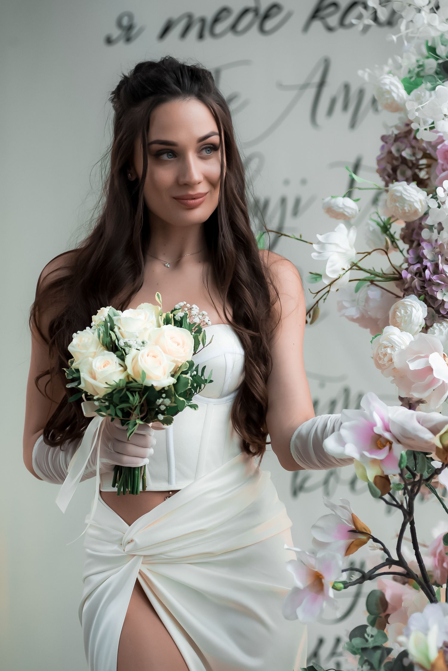 Bridal portrait with white flowers and soft lighting against text wall decor.